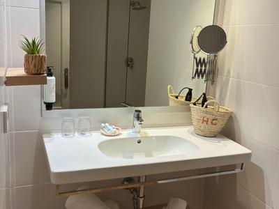 Moderne wastafel met grote spiegel, witte handdoeken en decoratieve planten in de badkamer.