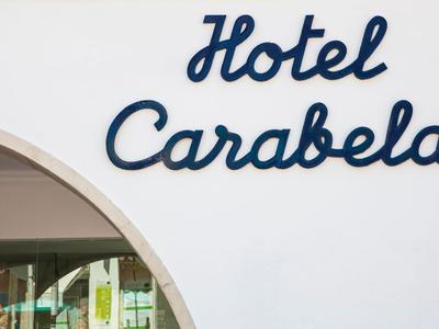 Blauwe tekst 'Hotel Carabela' op witte muur boven een boog