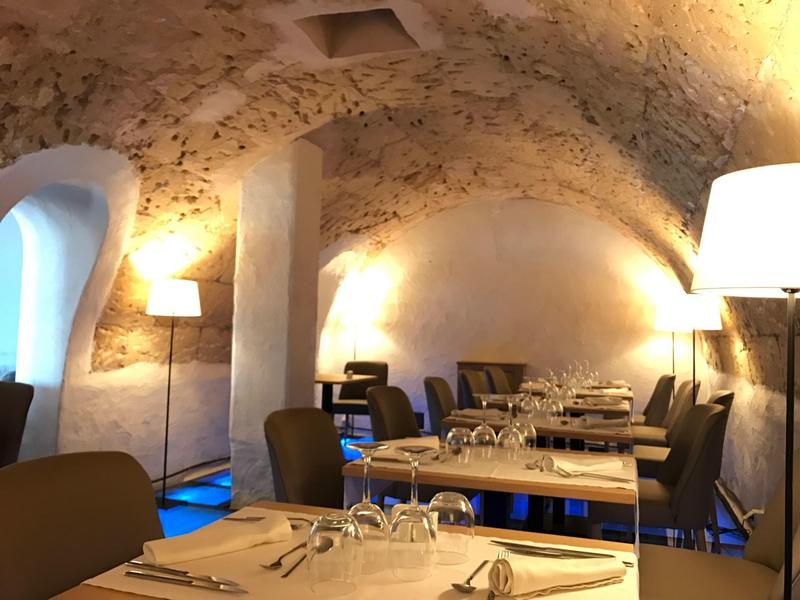 Pohodlná jídelna se klenutým stropem a elegantně prostřenými stoly v hotelové restauraci.