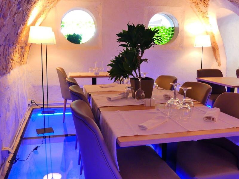 Moderní jídelní prostor se skleněnou podlahou a teplým ambientním osvětlením.