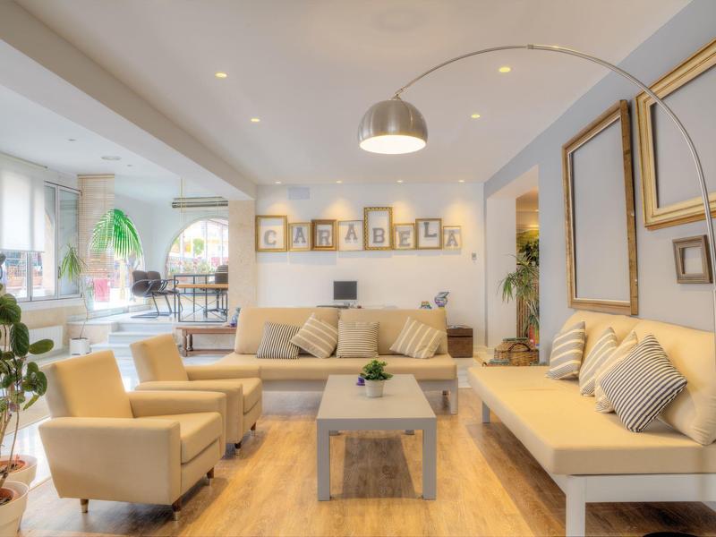 Světý, moderní obývací pokoj se žlutým nábytkem, dřevěnou podlahou a rostlinami v hotelu.