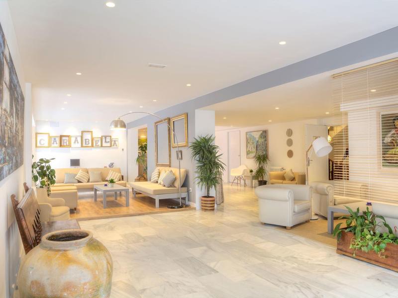 Světlá hotelová hala s pohodlným posezením, rostlinami a teplými barvami