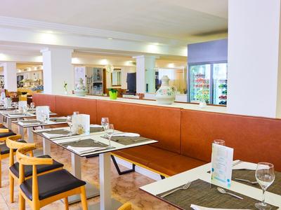 Nowoczesna restauracja z stołami, krzesłami i długą ławką dla gości.