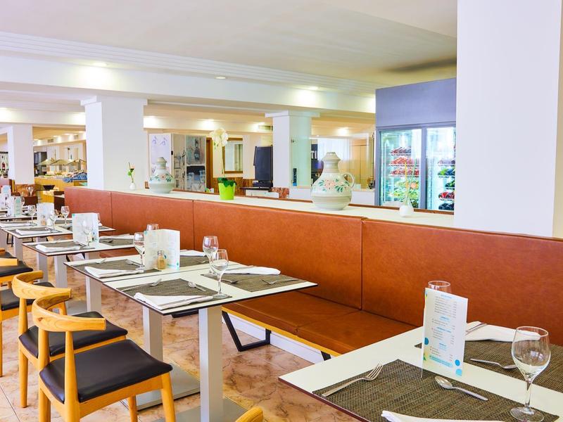 Nowoczesna restauracja z stołami, krzesłami i długą ławką dla gości.