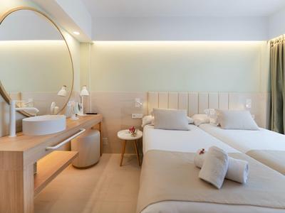 Modernes Schlafzimmer mit zwei Betten, großem runden Spiegel, hellem Holz und sanfter Beleuchtung.