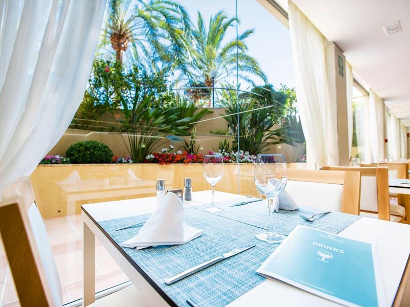 Bright dining area with a view of lush palm trees and plants.