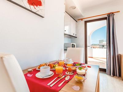 Frühstückstisch mit Essen und Getränken an Fenster mit Blick auf Balkon und Stadt.