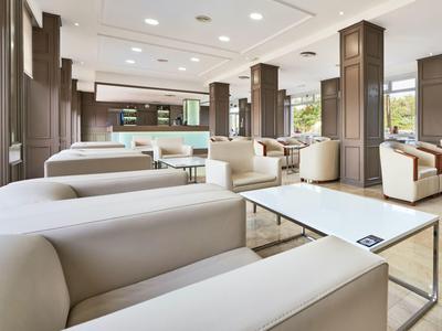 Nowoczesny hotelowy salon z wygodnymi sofami, stołami i dużymi oknami.