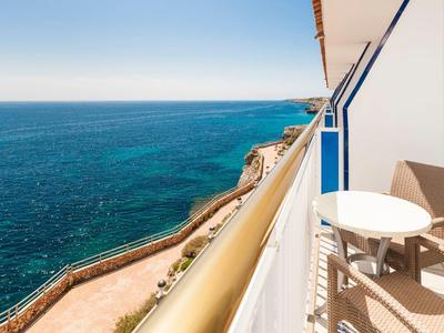 Widok z balkonu z krzesłami i stołem na niebieskie morze i wybrzeże.