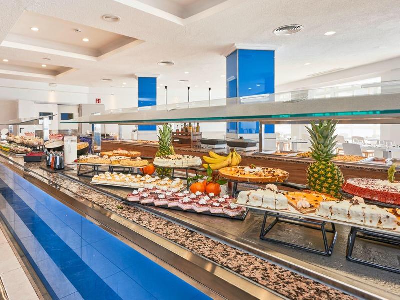 Bufet z różnorodnymi potrawami w jasnej, nowoczesnej restauracji z niebieskimi akcentami.