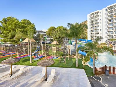 Modernes Hotelresort mit Wasserrutschen, Spielplatz und Hochhäusern vor blauem Himmel.