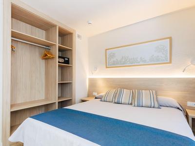 Camera d'albergo accogliente con letto matrimoniale, armadio a muro e decorazioni neutre.