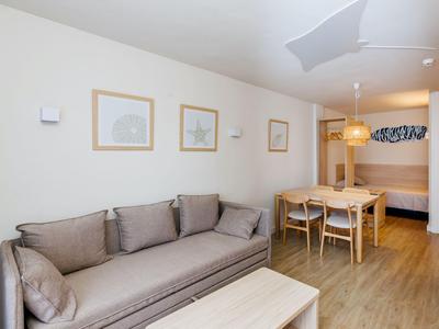 Camera d'hotel moderna arredata con divano, tavolo da pranzo, sedie e letto sullo sfondo.