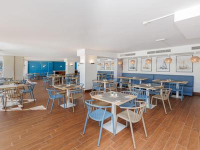 Sala da pranzo moderna con sedie blu, pavimento in legno e immagini decorative di fenicotteri sulla parete.