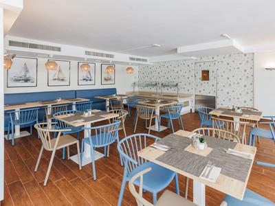 Una sala da pranzo moderna con sedie blu e immagini nautiche sulla parete.