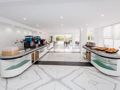 Moderne hotel lobby met buffetstations, koffiemachines en een lichte marmeren vloer.