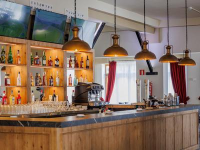 Moderne hotelbar met houten bar, verlichte schappen en koperen plafondlampen.