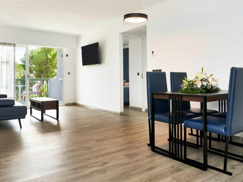 Spacious living and dining area with wooden floor, blue furniture, and balcony access.