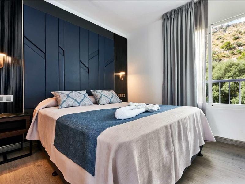 Modern bedroom with blue upholstered bed and view through the window.