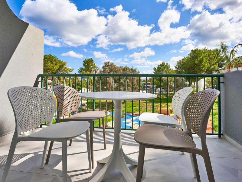 Terrace with modern table and four chairs overlooking pool and trees.