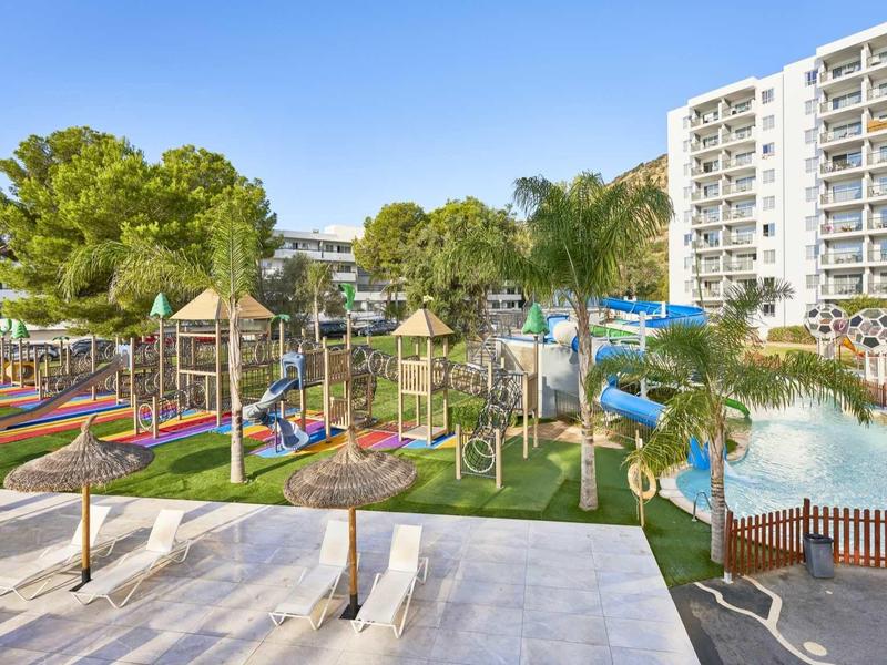 Amusement park with water slides and playground next to hotels and green areas.