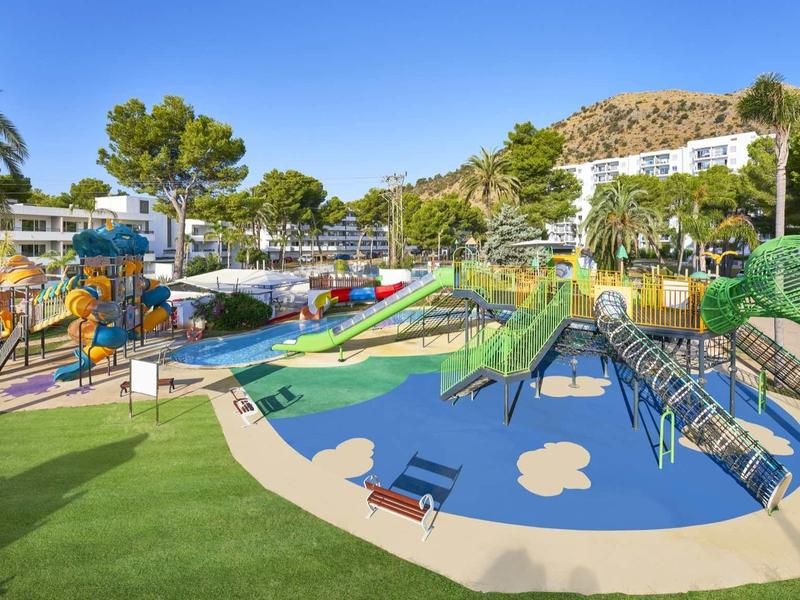 Colorful children's playground with slides and climbing frames in a sunny holiday resort.