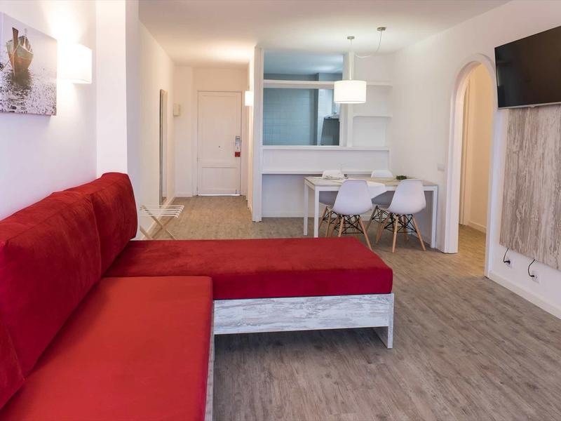 Modern living room with red sofa, dining table, and wall-mounted TV.