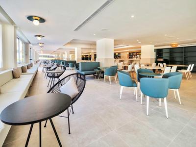 Bright hotel lounge area with blue upholstered chairs and black tables.