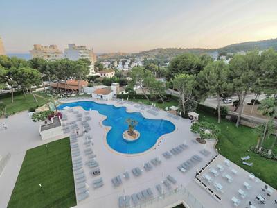 Hotel pool with sun loungers and surrounding garden in a peaceful resort area.