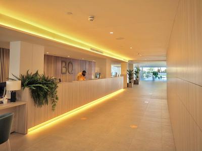 Modern hotel reception with a long desk, subtle lighting, and plants.