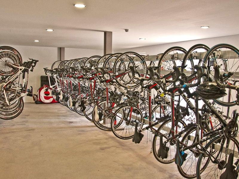 Bicycles hang neatly on wall mounts in an organized hotel bike storage area.