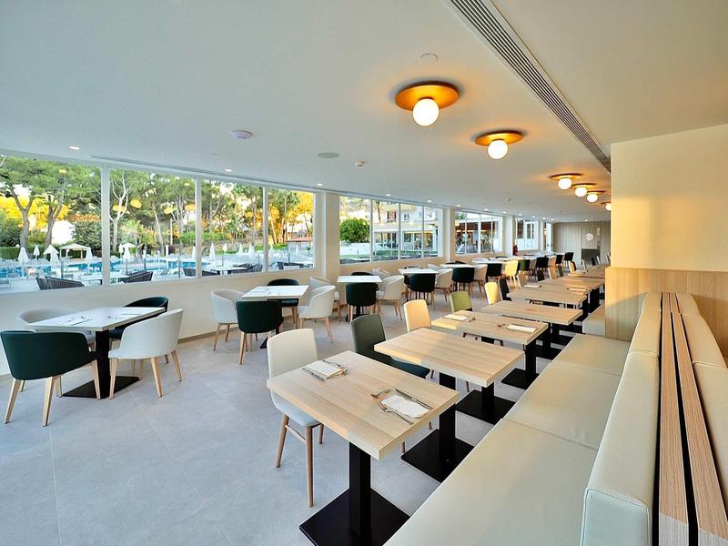 Bright modern restaurant with large windows and stylish seating areas next to a street.