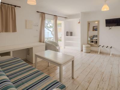 Espace de vie moderne et lumineux avec canapé, table, chaise et grande porte vitrée donnant sur l'extérieur.