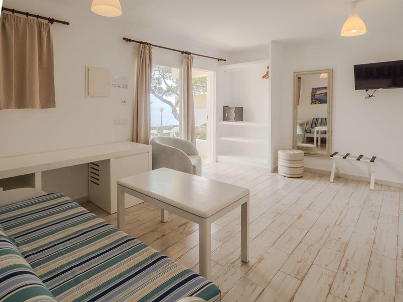 Espace de vie moderne et lumineux avec canapé, table, chaise et grande porte vitrée donnant sur l'extérieur.