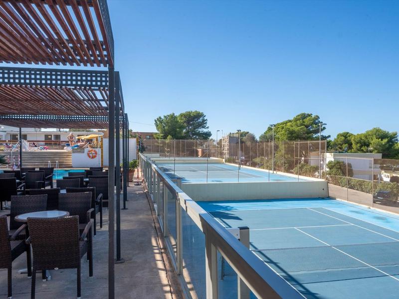 Terrasse avec coin salon à côté d'une piscine extérieure sous un ciel bleu clair.