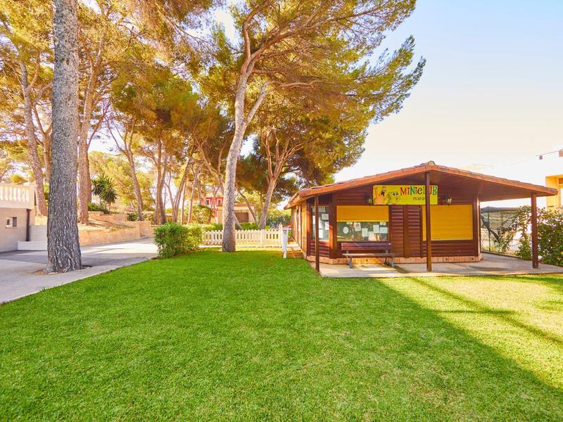 Zielony park z drewnianą altaną i drzewami pod czystym niebem.