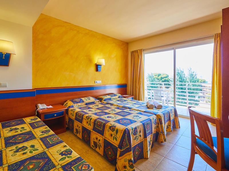 Jasny pokój hotelowy z bliźniaczymi łóżkami i balkonem z widokiem na naturę.