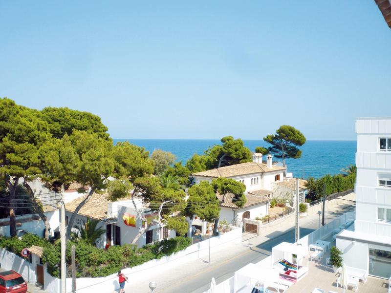 Vista di un quartiere di case vacanze con alberi e mare sullo sfondo sotto un cielo limpido.