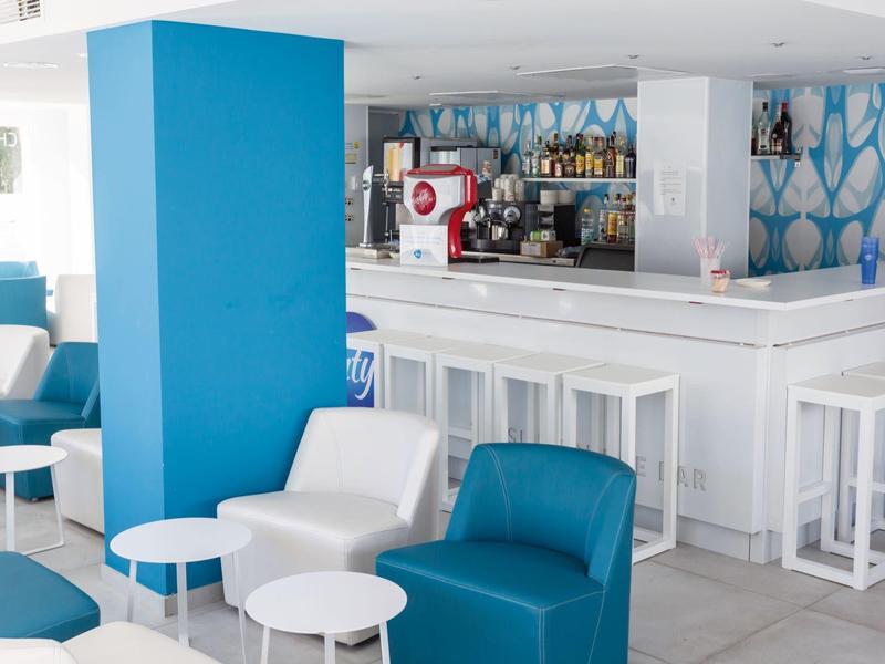 Area bar moderna dell'hotel con poltrone bianche e blu e tavoli bianchi.