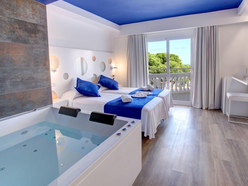 Camera d'hotel moderna con letto matrimoniale, vasca idromassaggio e balcone con vista.