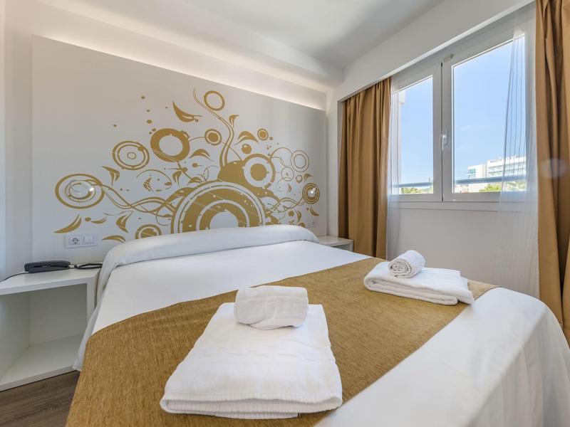 Camera d'hotel moderna con letto matrimoniale, arte decorativa a parete e grandi finestre con vista esterna.