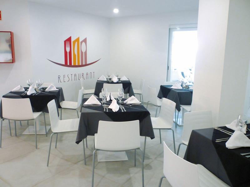 Ristorante moderno con tavoli coperti di nero e sedie bianche in una stanza luminosa