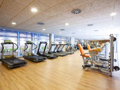Modern fitness room with treadmills and strength machines in a hotel.