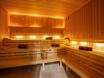 Innenraum einer Holzsauna mit mehrstufigen Sitzbänken und warmem, gelbem Licht.