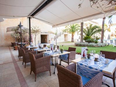 Gemütliche Außenanlage mit gedeckten Tischen, Rattanstühlen und grünem Garten in hellem Ambiente.