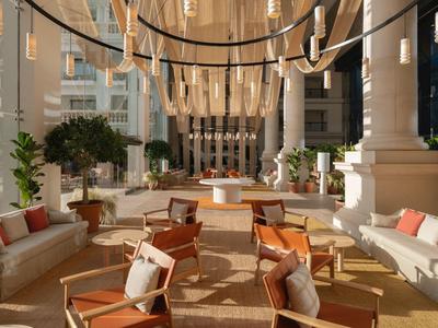 Lobby de hotel elegante y soleada con sillones cómodos y candelabros modernos.