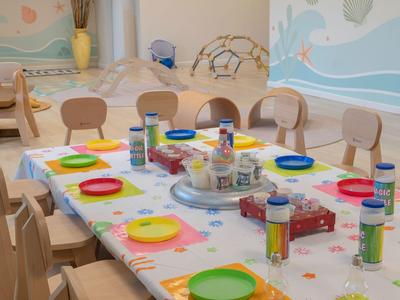 Mesa de desayuno colorida con platos y latas de bebida en una habitación de hotel para niños.