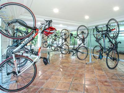 Bicycles hanging on walls in a well-lit bike storage room with tiled floor.