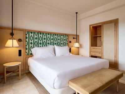 Habitación de hotel moderna con cama grande, muebles de madera y cabecero con diseño verde.