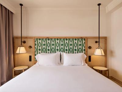 Habitación de hotel moderna con cama grande y pared cabecero de patrón geométrico.